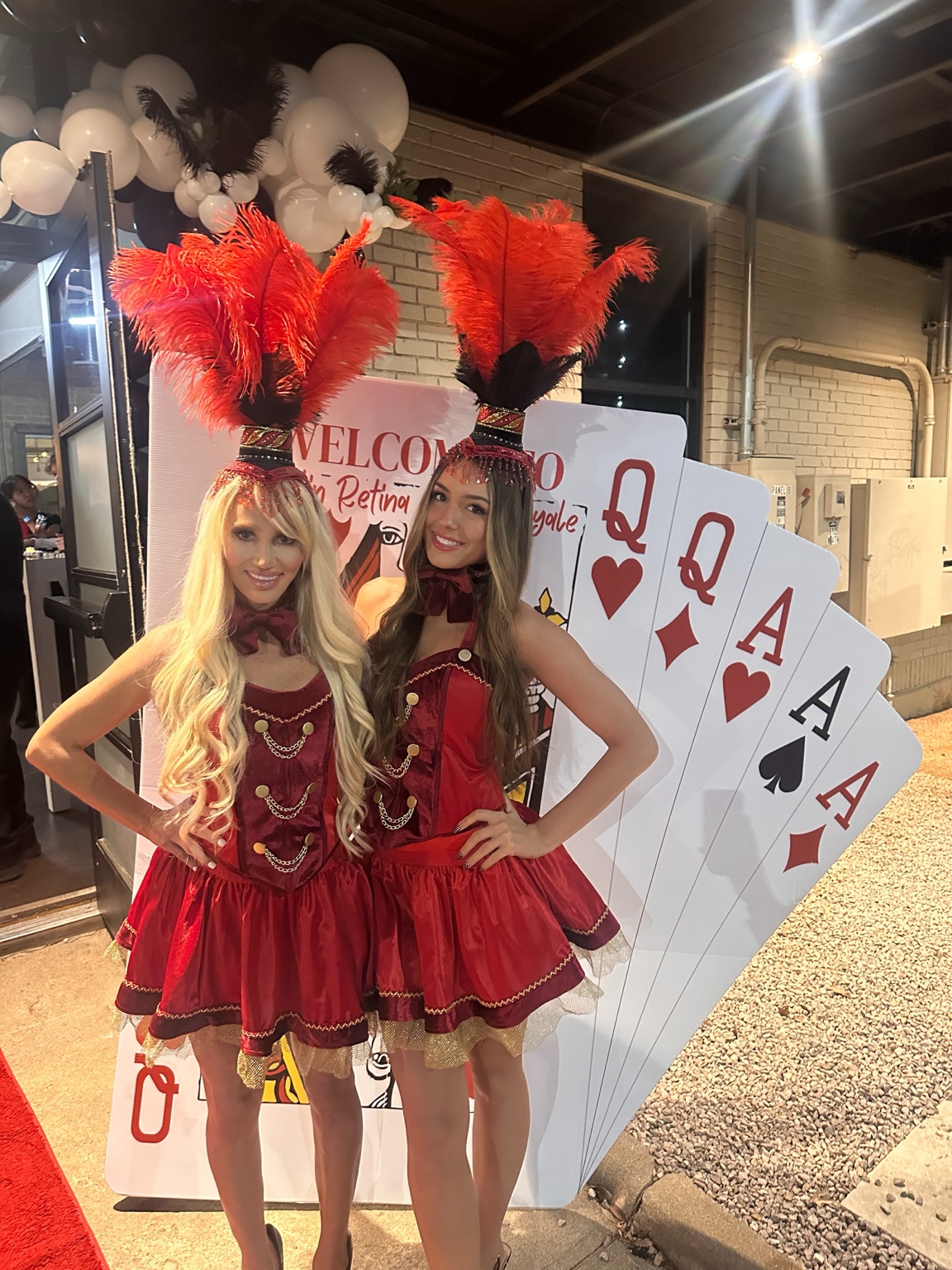 Two representatives from The HPPI Agency, Inc. in coordinated casino-night attire beside oversized playing cards